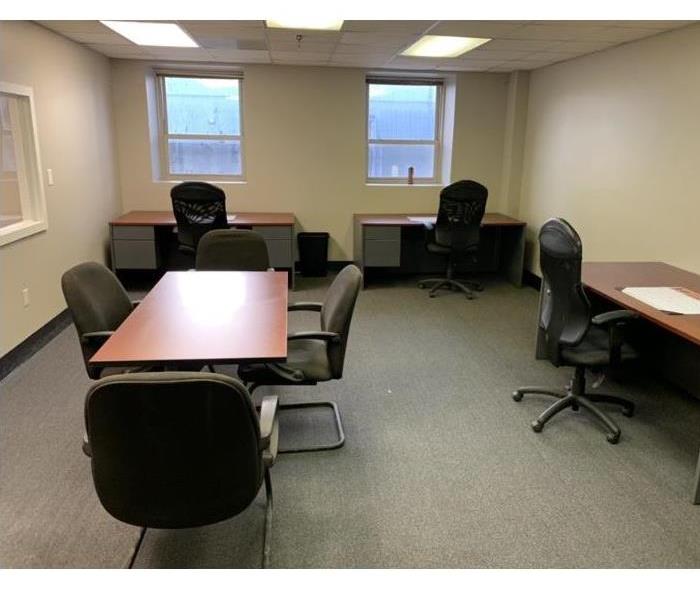 Taupe walls with grey carpet and desks set up with chairs for office 